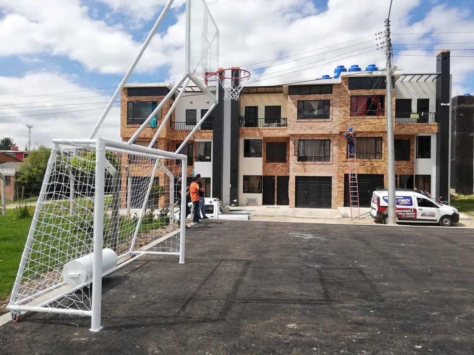 Arco de fútbol con malla y estructura de baloncesto instalados en una cancha de asfalto