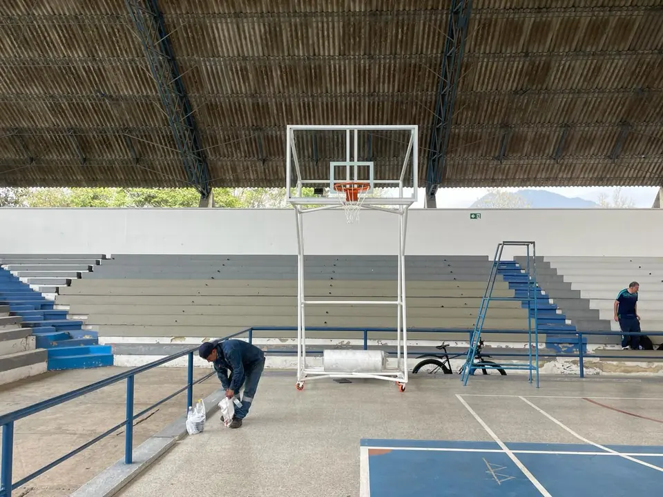 Técnico instalando una estructura de baloncesto móvil en un coliseo
